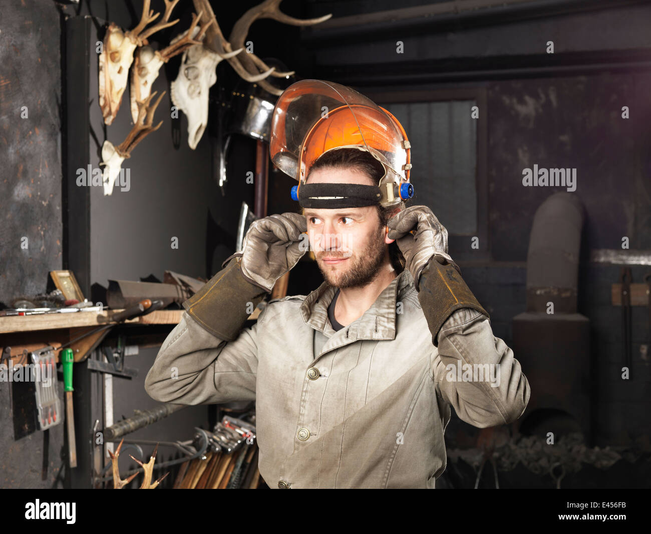 Blacksmith putting on a visor in workshop Stock Photo