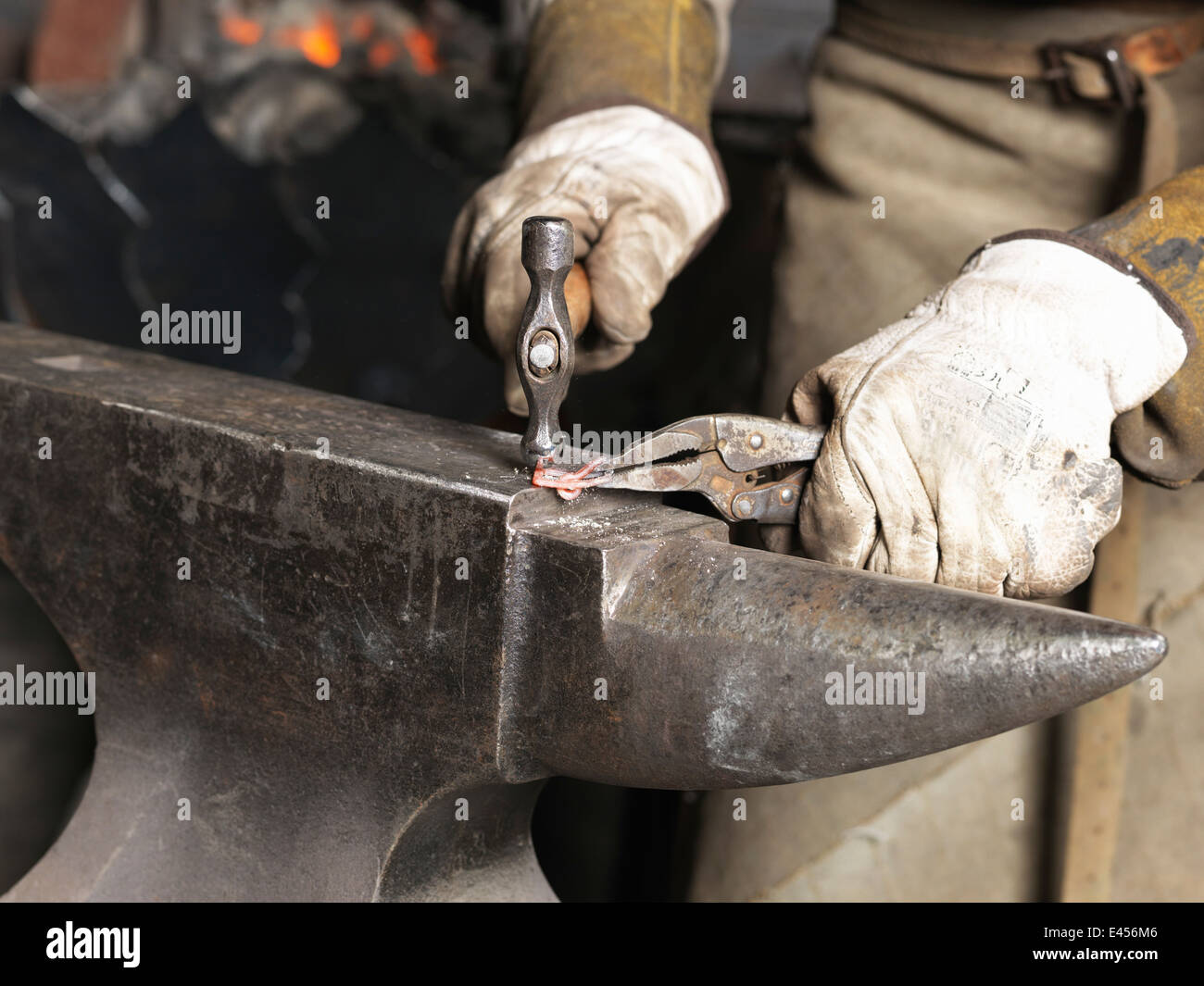 Cropped image of blacksmiths hands hammering red hot metal Stock Photo