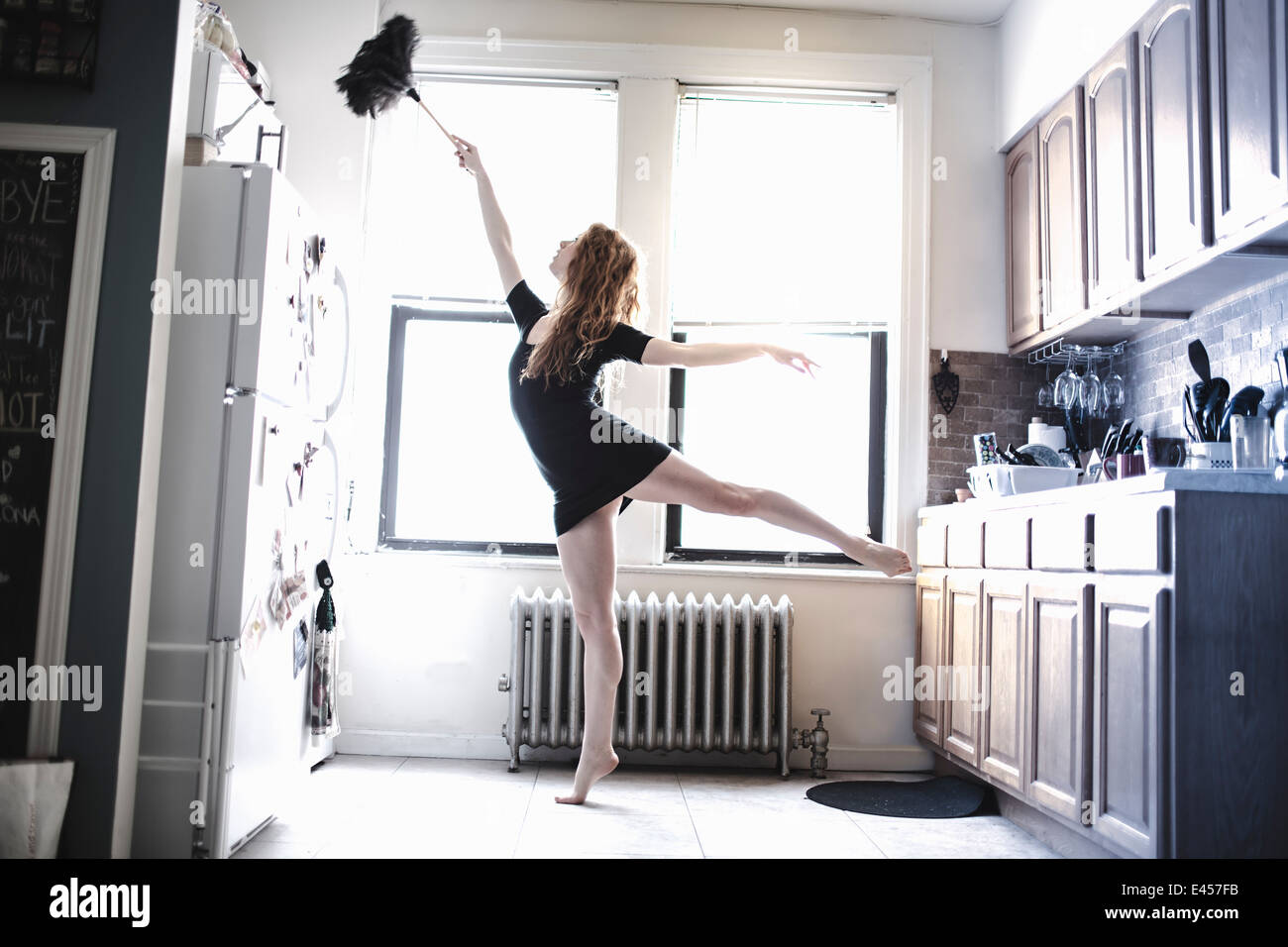 Modern dancer dusting her apartment Stock Photo