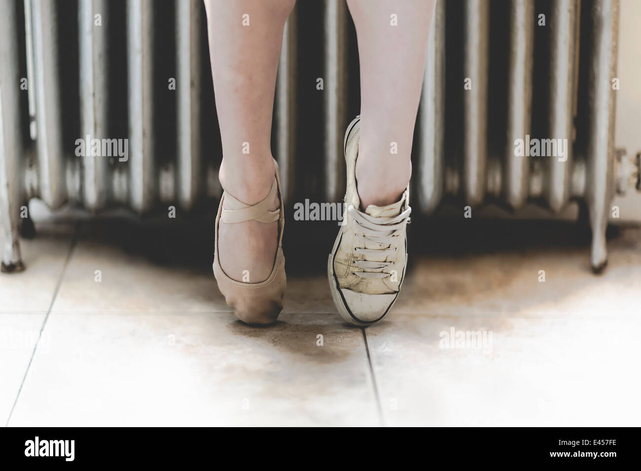 Dancer wearing one ballet shoe and one sneaker Stock Photo