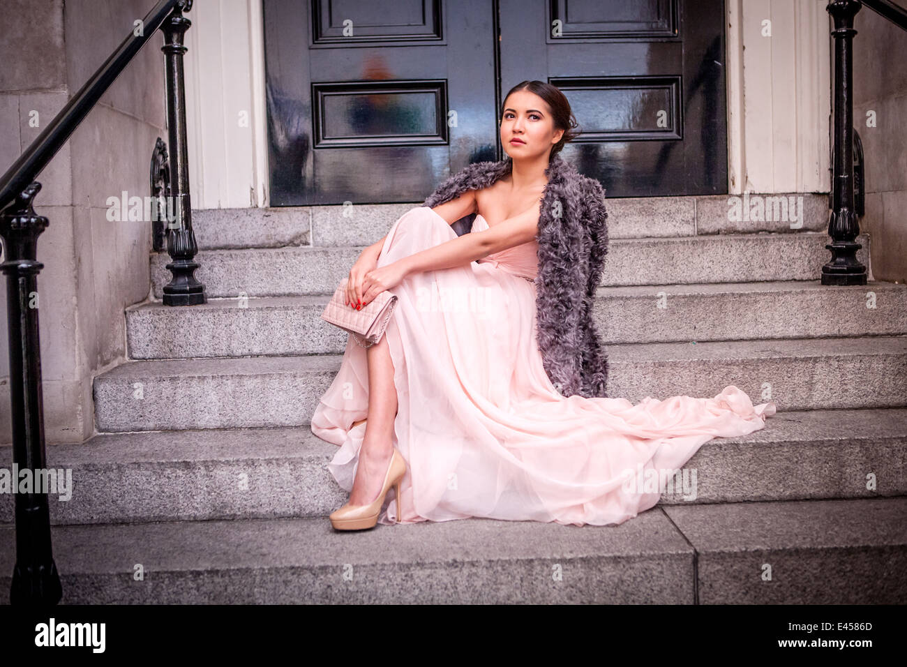 Portrait of young woman in evening gown sitting on steps Stock Photo