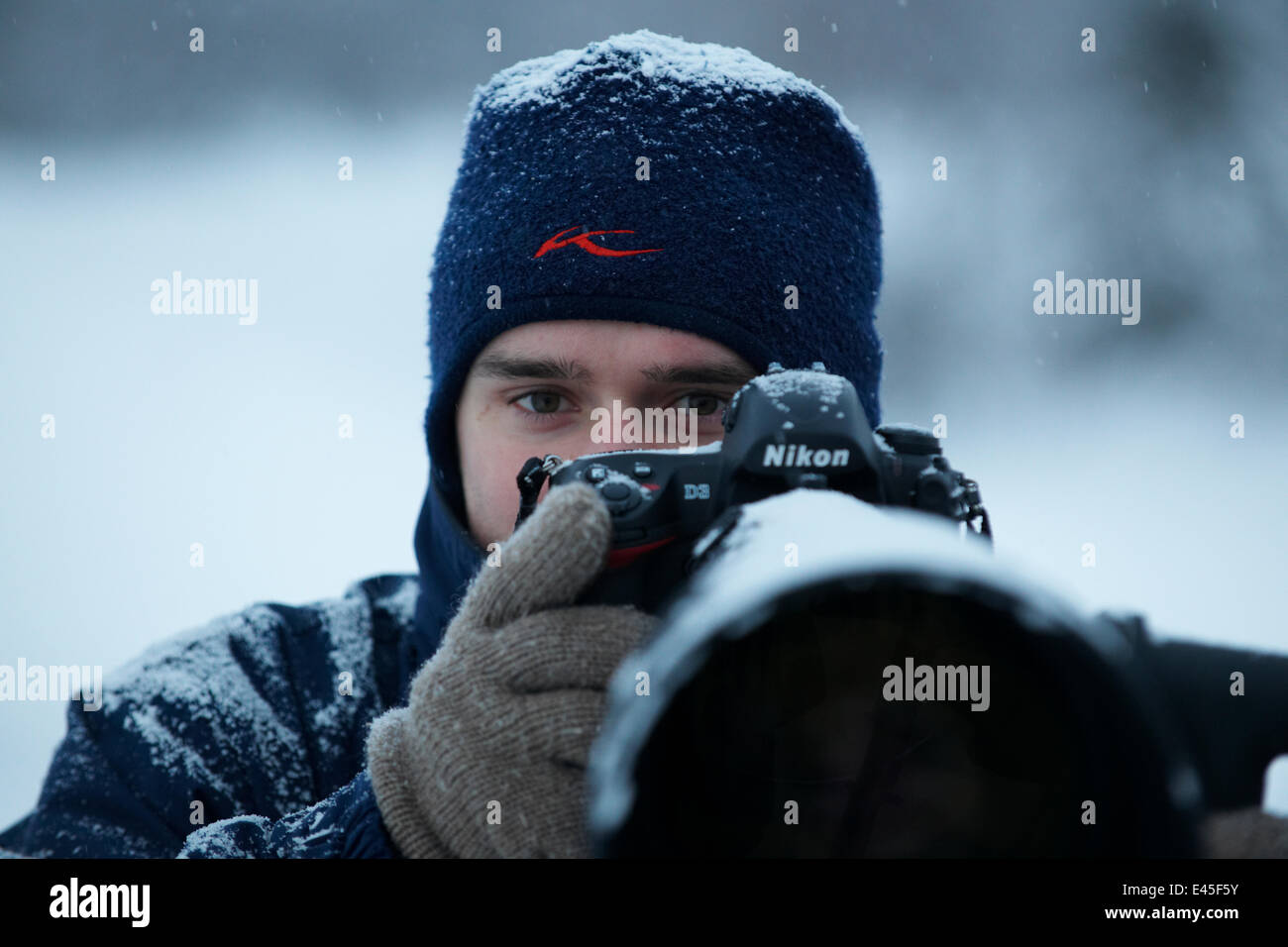 Photographer, Sven Zacek, with camera, in snow, Finland, February 2009 Stock Photo