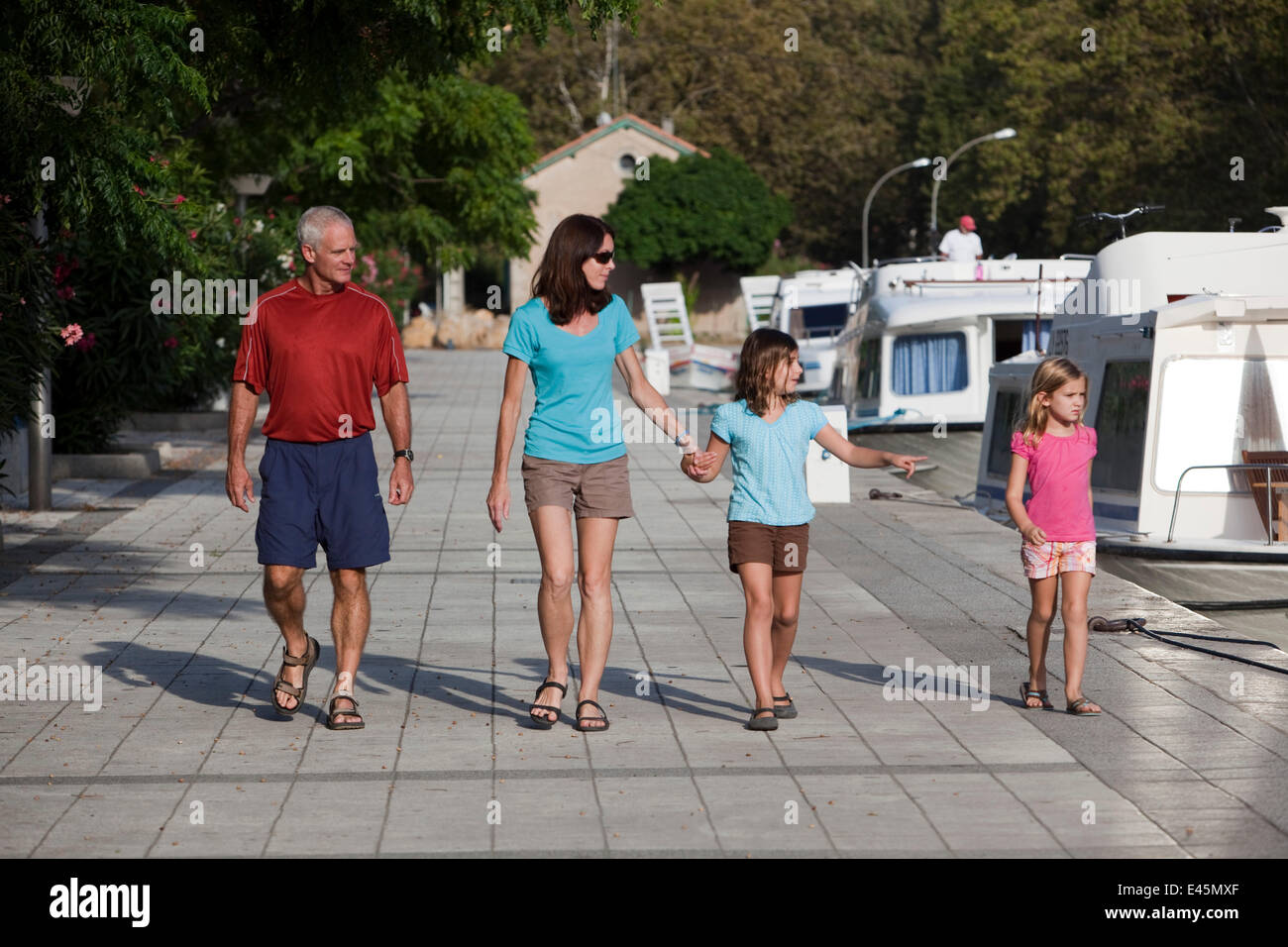 Family walking alongside boats, Canal Du Midi near Carcassonne, Languedoc, France. July 2009. Model and property released. Stock Photo