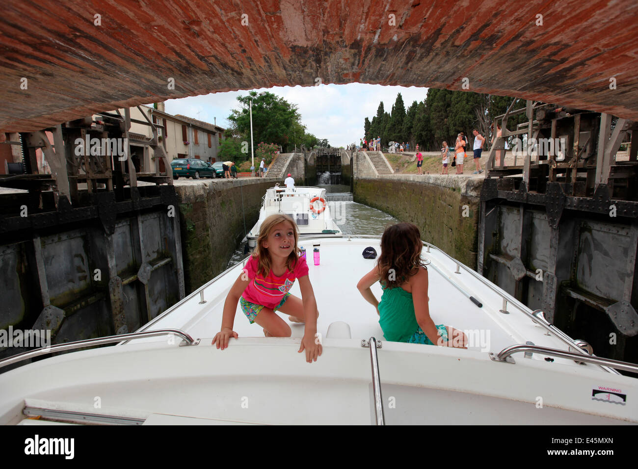 Girls on boat, passing out of a lock on the Canal Du Midi near Capestang, Languedoc, France. July 2009. Model and property released. Stock Photo