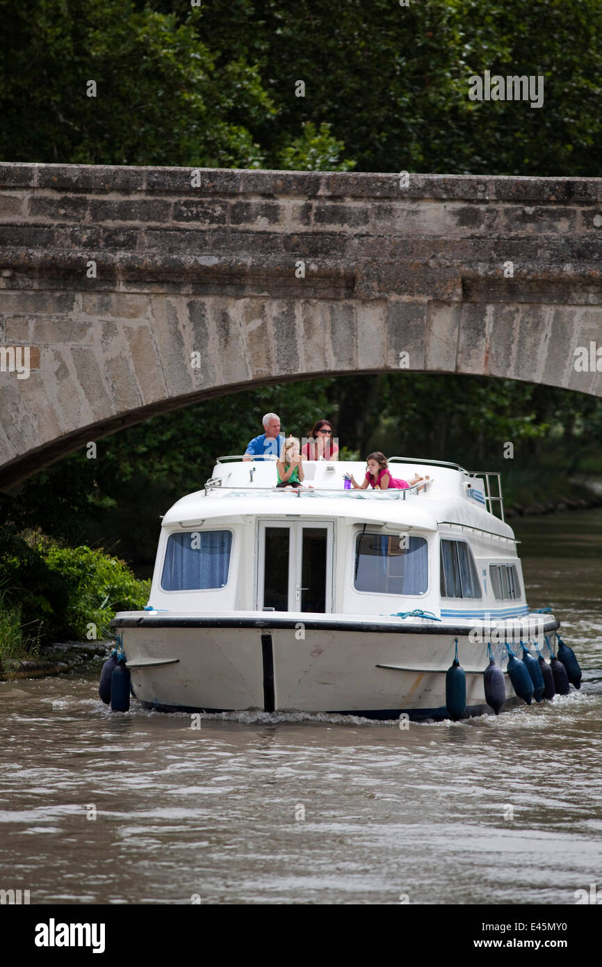 Family cruising under a bridge on the Canal Du Midi near Capestang, Languedoc, France. July 2009. Model and property released. Stock Photo