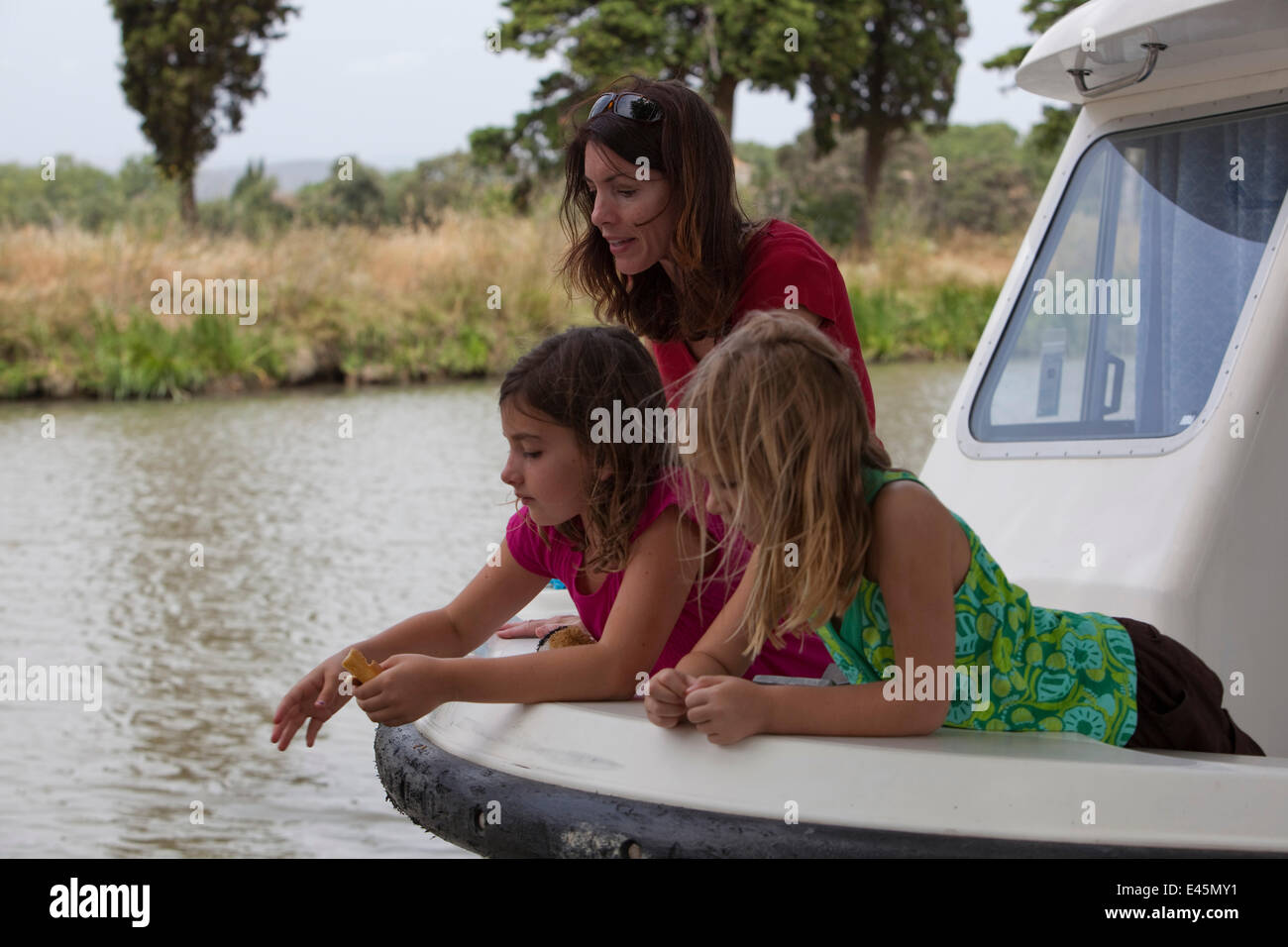 Mother and daughters on bow of a boat cruising on the Canal Du Midi near Capestang, Languedoc, France. July 2009. Model and property released. Stock Photo