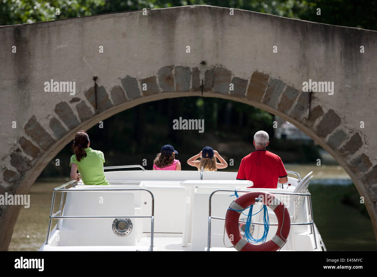 Family cruising under bridge on the Canal Du Midi near Pechlairier, southern France. July 2009. Model and property released. Stock Photo