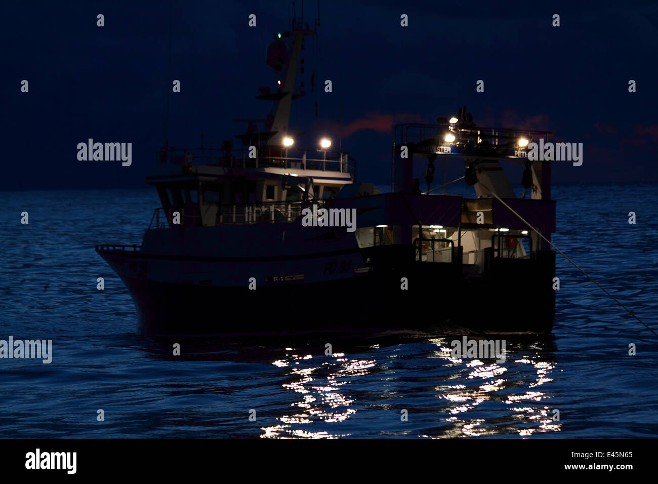 Fishing vessel Harvester trawling at twilight on the North Sea. February 2010. Property released. Stock Photo