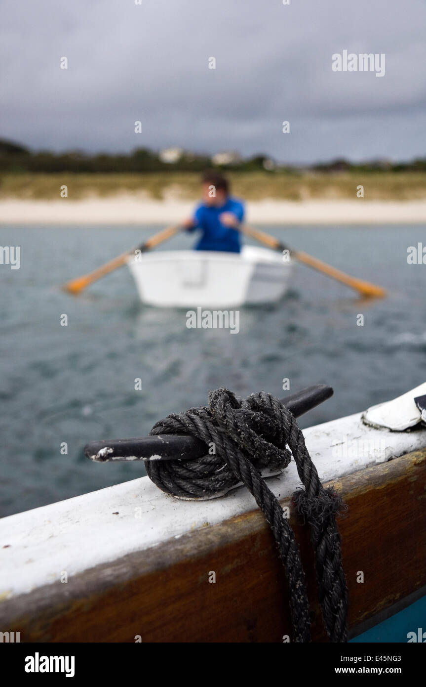 Man rowing a tender towards the beach from a boat off St. Martin's, Isles of Scilly, UK. Model Released Stock Photo