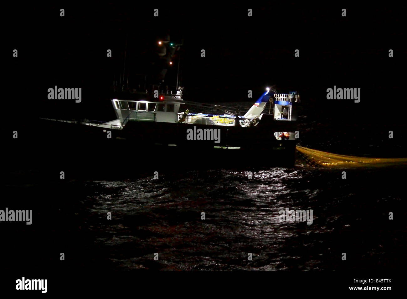 Trawler hauling net onboard during night fishing. September 2010. Property released. Stock Photo