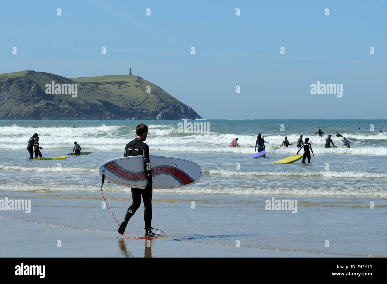 Surfers heading out into the waves at Polzeath beach. Cornwall, UK, April 2010. Stock Photo