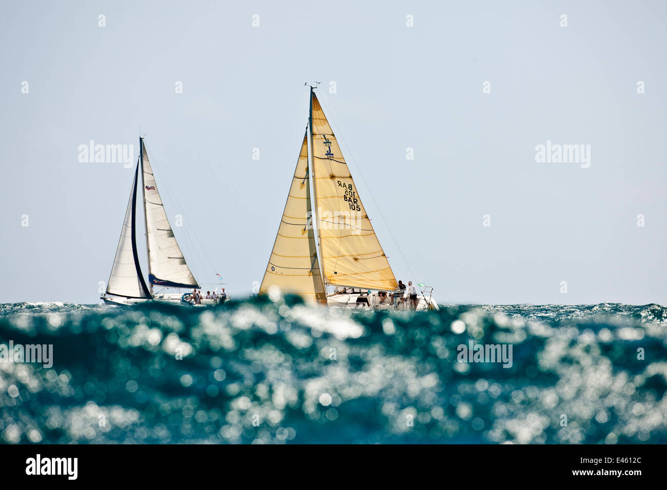 Two yachts obscured by glistening wave during the Grenada Sailing Festival, Caribbean, January 2010. Stock Photo
