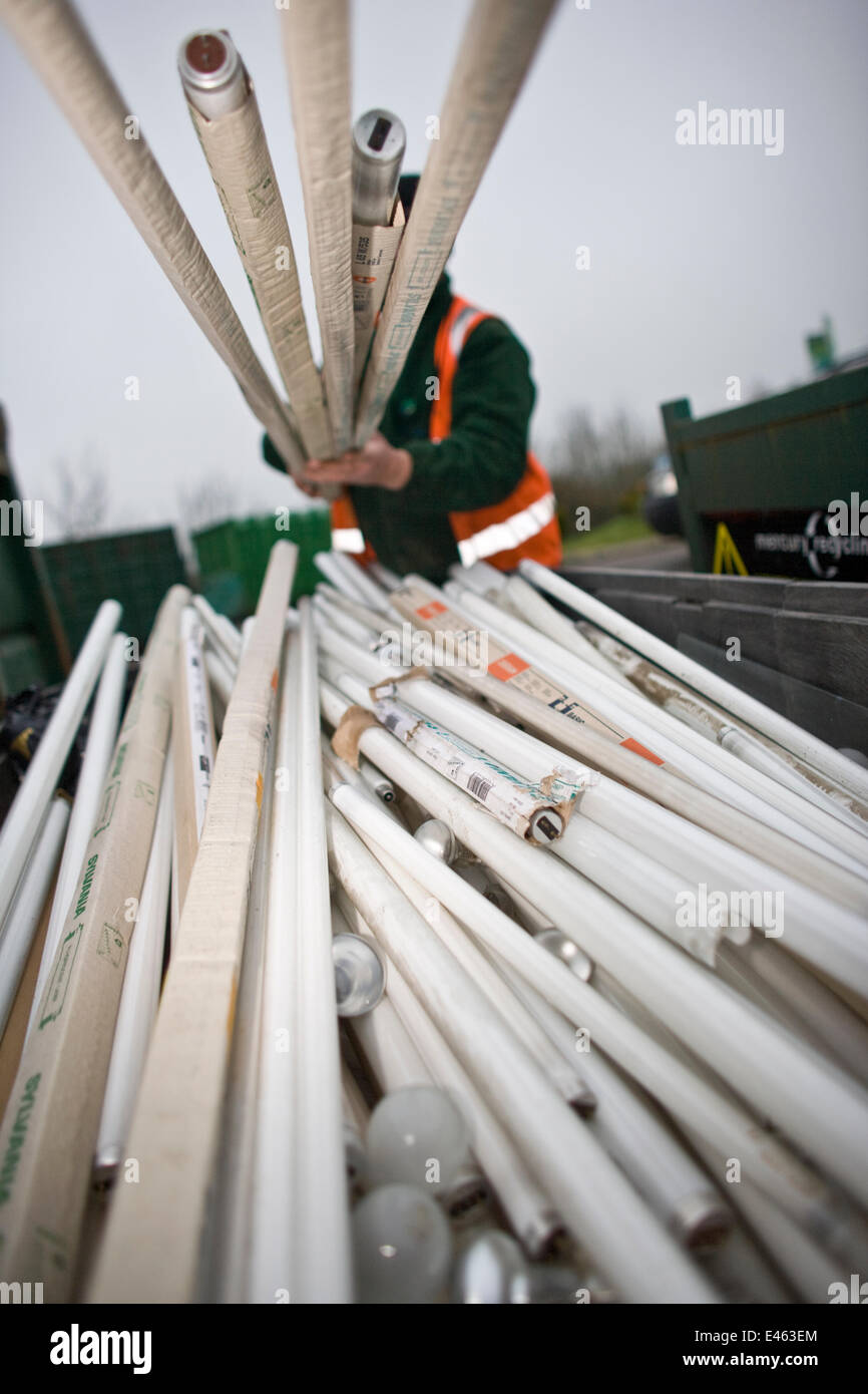 Man lifting fluorescent light tubes at a recycling centre, Stroud
