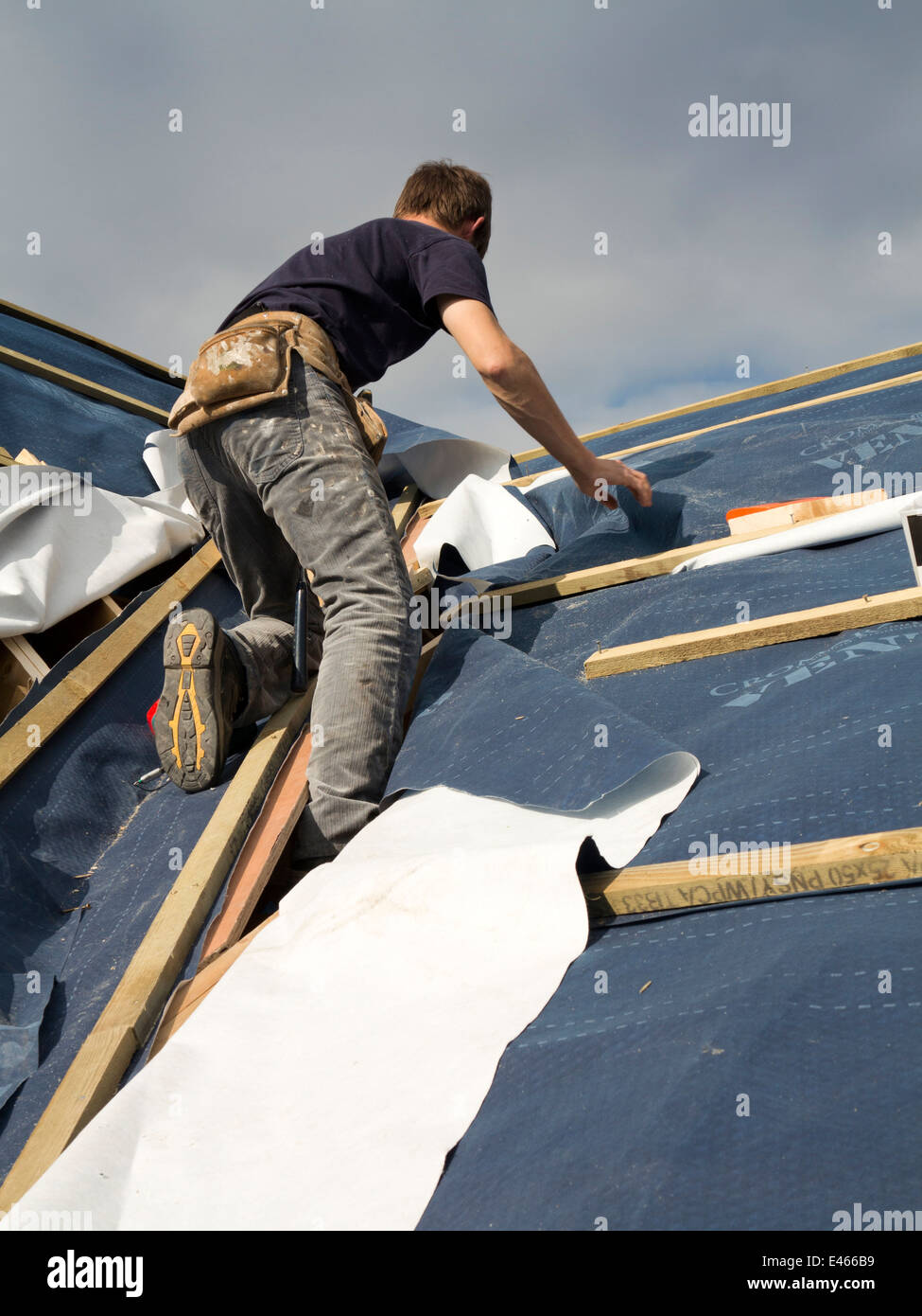 self building house, constructing roof, man trimming breathable roofing
