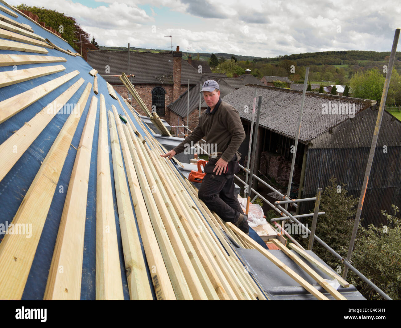 self building house, constructing roof, man fixing roofing laths with