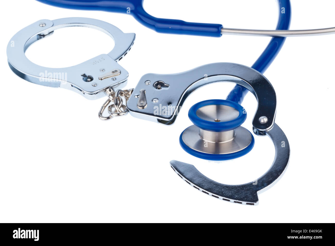 Handcuffs and a stethoscope lying on a white background. Stock Photo