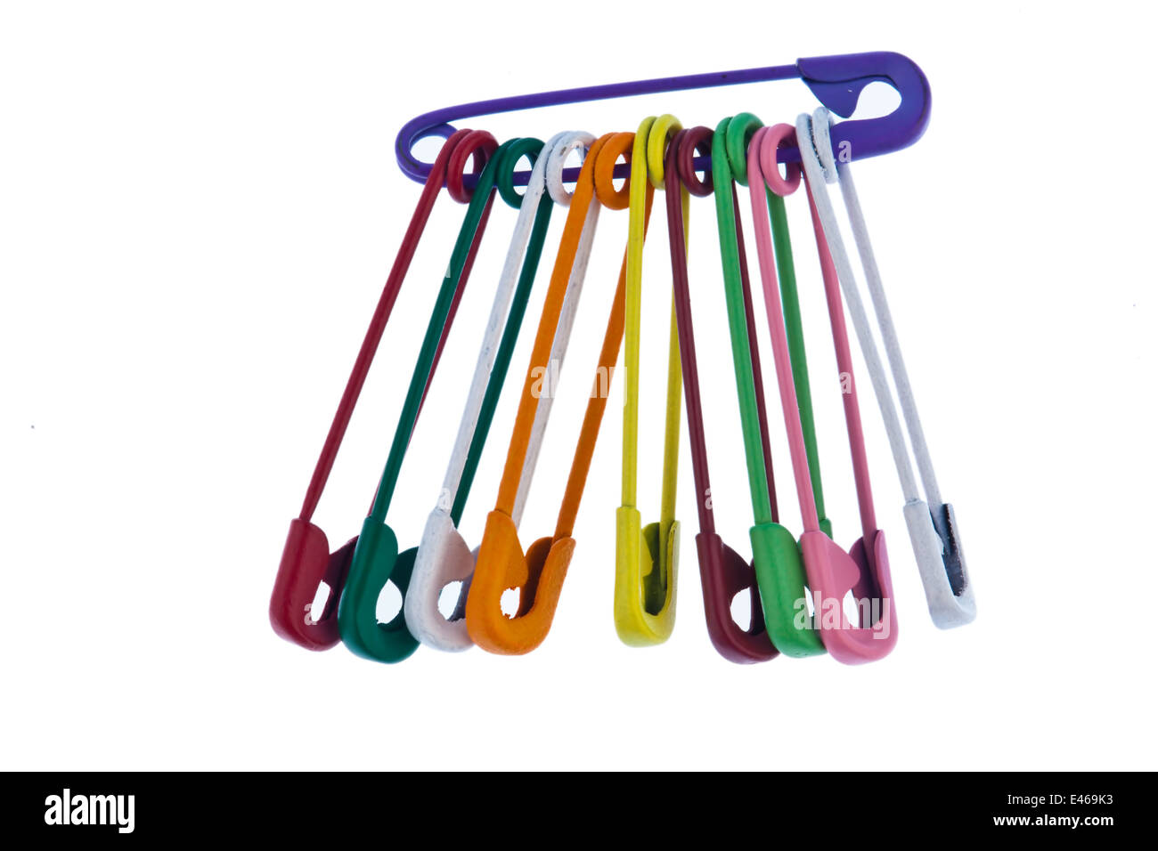 Lots of colorful safety pins lying on a white background Stock Photo
