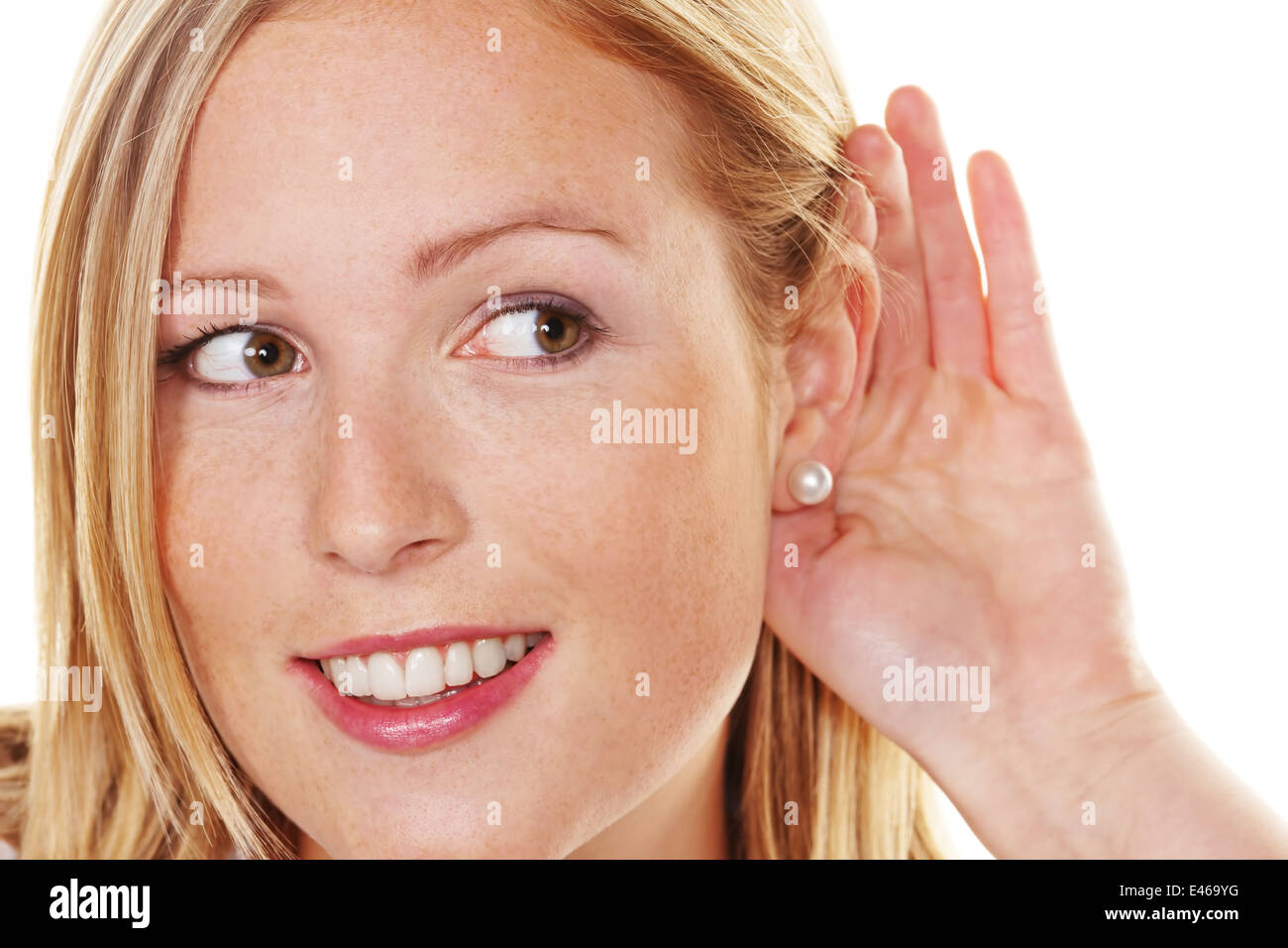 A young woman holds the hand behind the ear to listen. Stock Photo