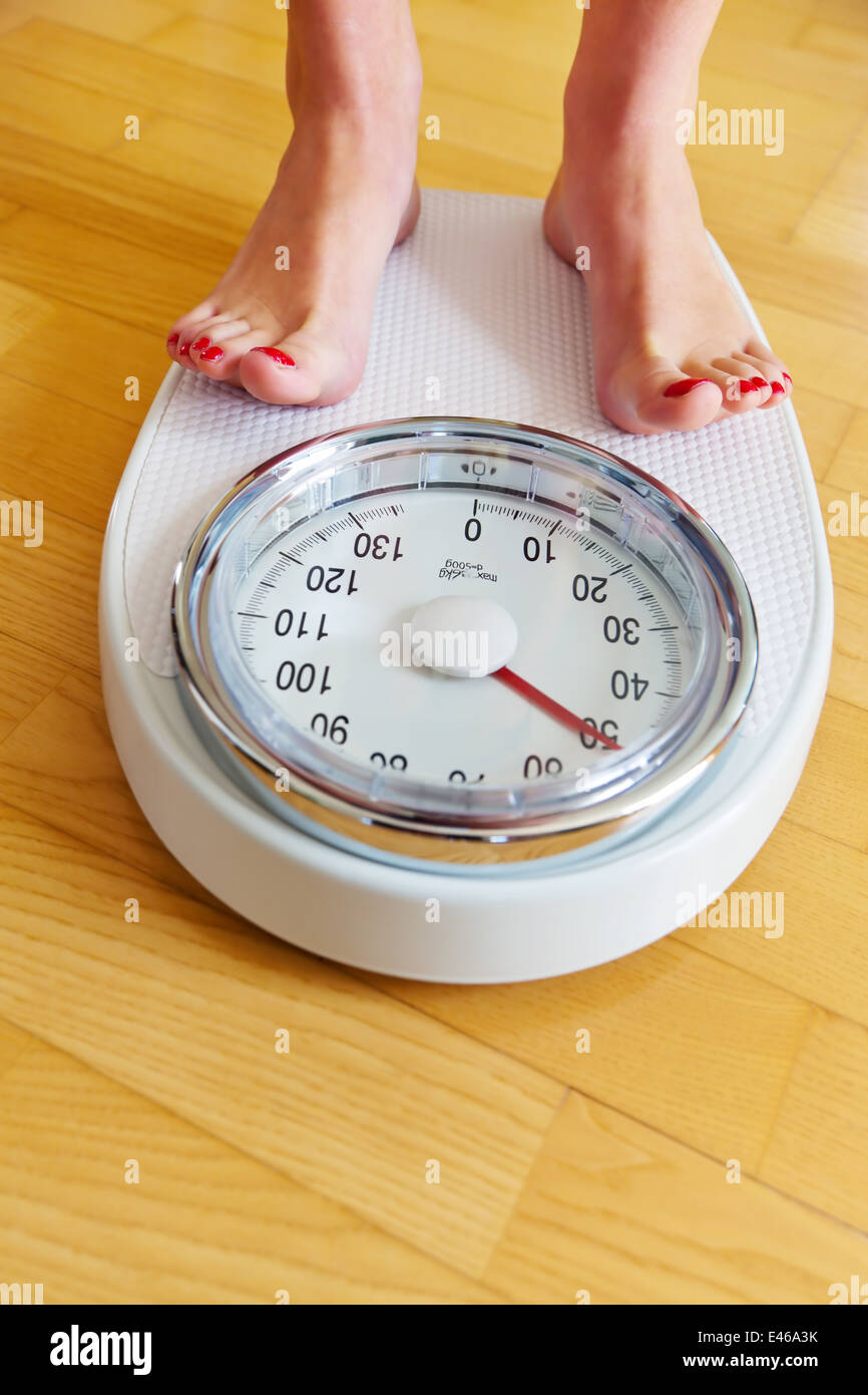 The feet of a woman standing on bathroom scales for weighing Stock Photo