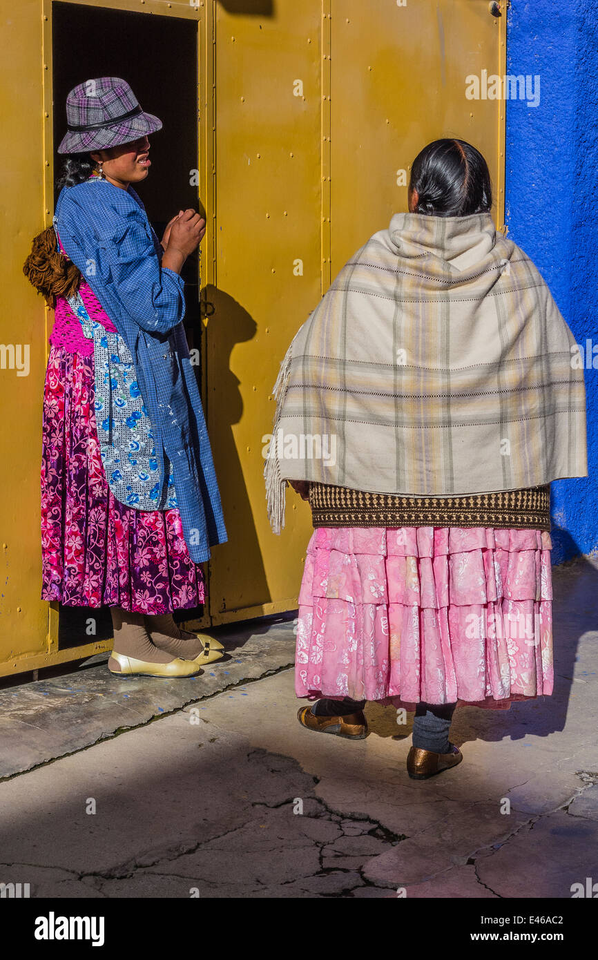 Two neighbor women, dressed in traditional clothes, talking outside the home of one of them in Copacabana, Bolivia. Stock Photo