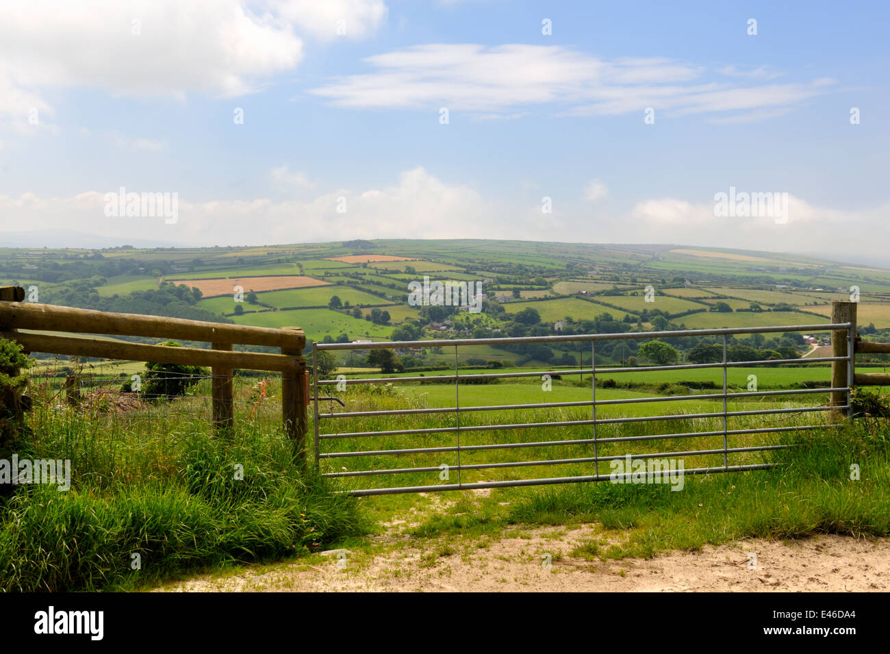 Farm field gate with hazy patchwork of hedgerow bound fields in distance, Wales, UK Stock Photo