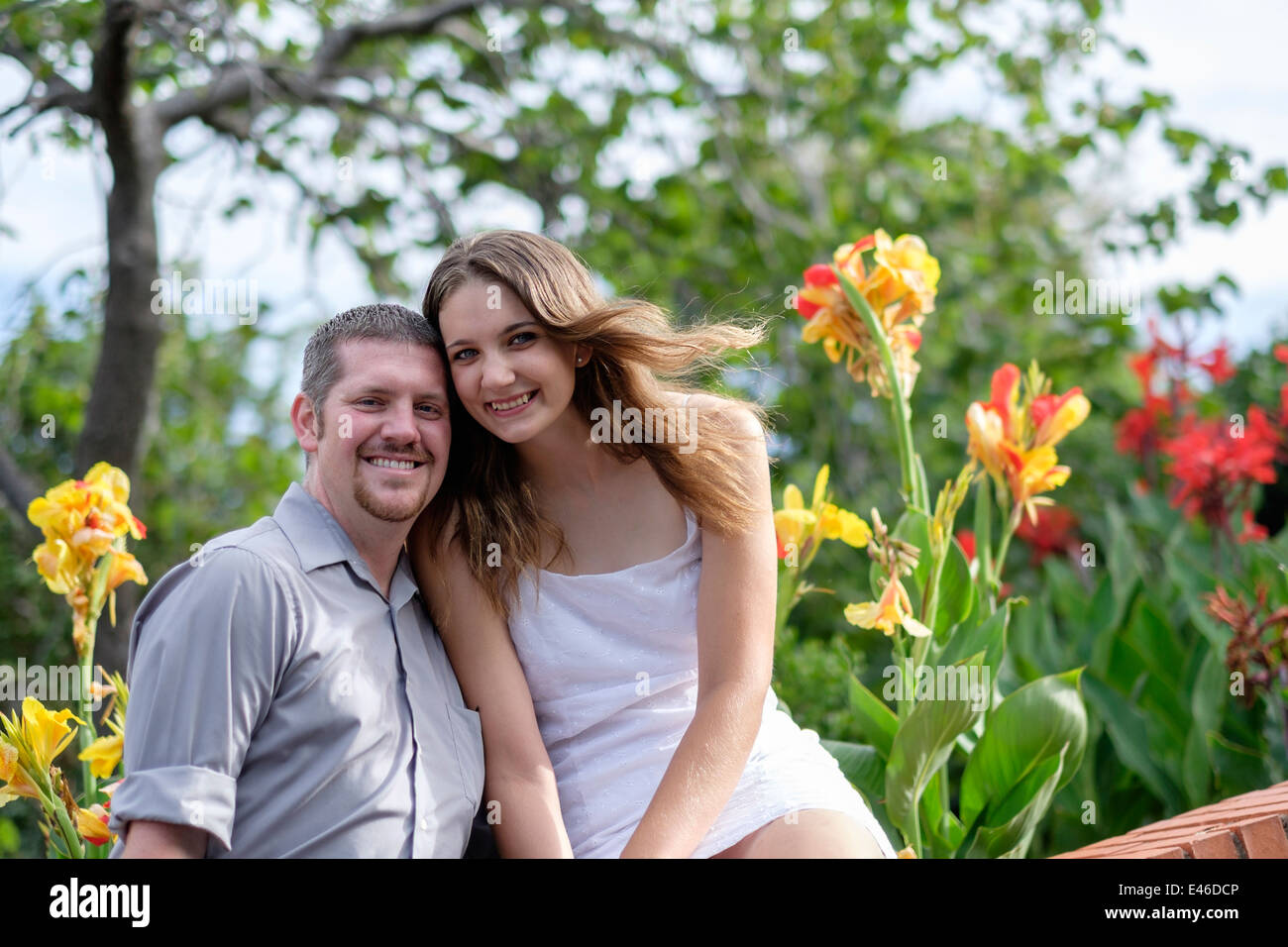 A happy, loving couple in their 20s pose for engagement pictures in a beautiful park surrounded by colorful blooming Irises. USA. Stock Photo
