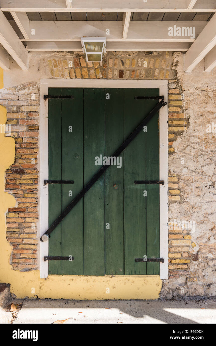 A colorful green wooden door inset into the dilapidated  crumbling fascade of a home in Frederiksted, St. Croix, U.S. Virgin Islands. USVI, U.S.V.I. Stock Photo