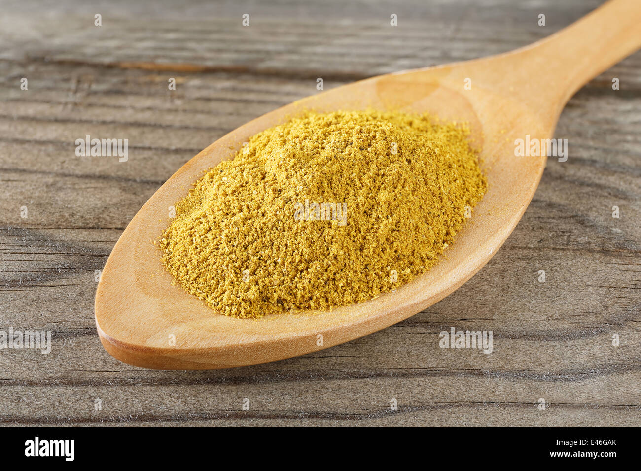 closeup macro wooden spoon with curry powder Stock Photo