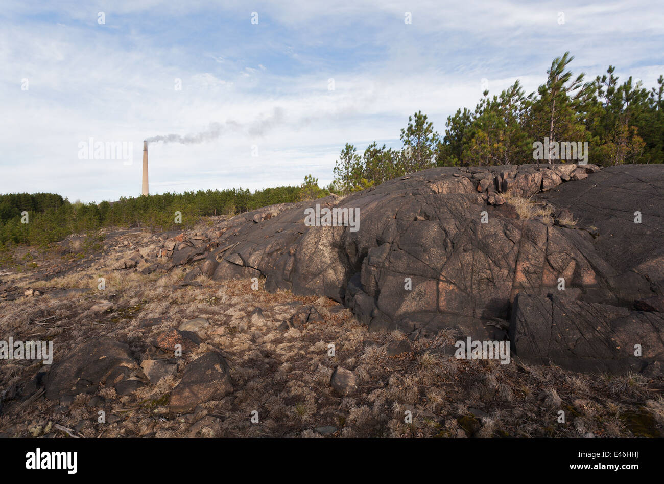 Pollution has blackened exposed rock in Sudbury near the Vale Mining operations. The Superstack can be seen in the distance. Stock Photo