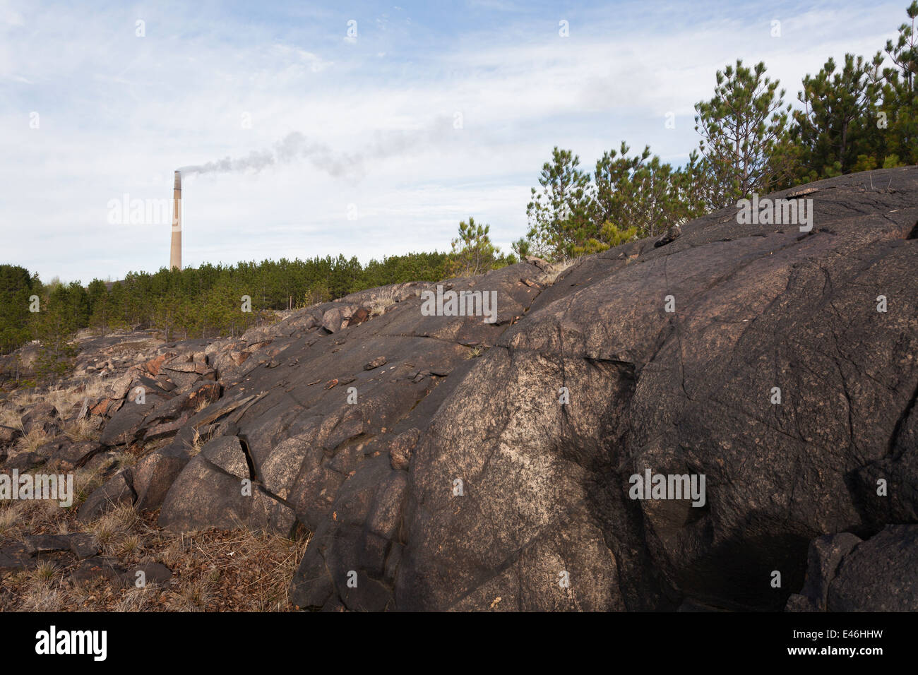 Pollution has blackened exposed rock in Sudbury near the Vale Mining operations. The Superstack can be seen in the distance. Stock Photo