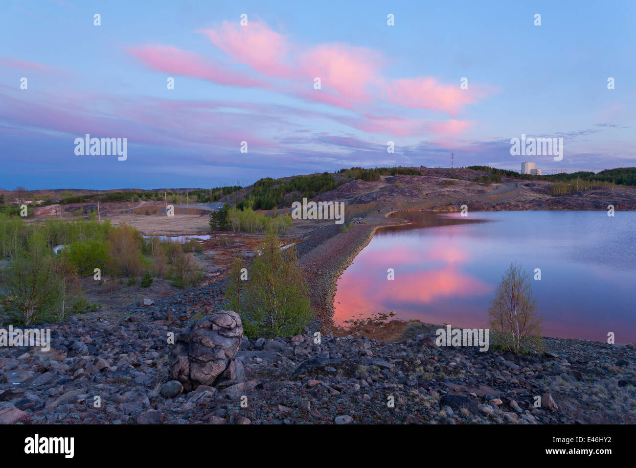 Elevated view of a tailings pond leaking into the surrounding marshland from a hilltop during a colourful sunset. Sudbury. Stock Photo
