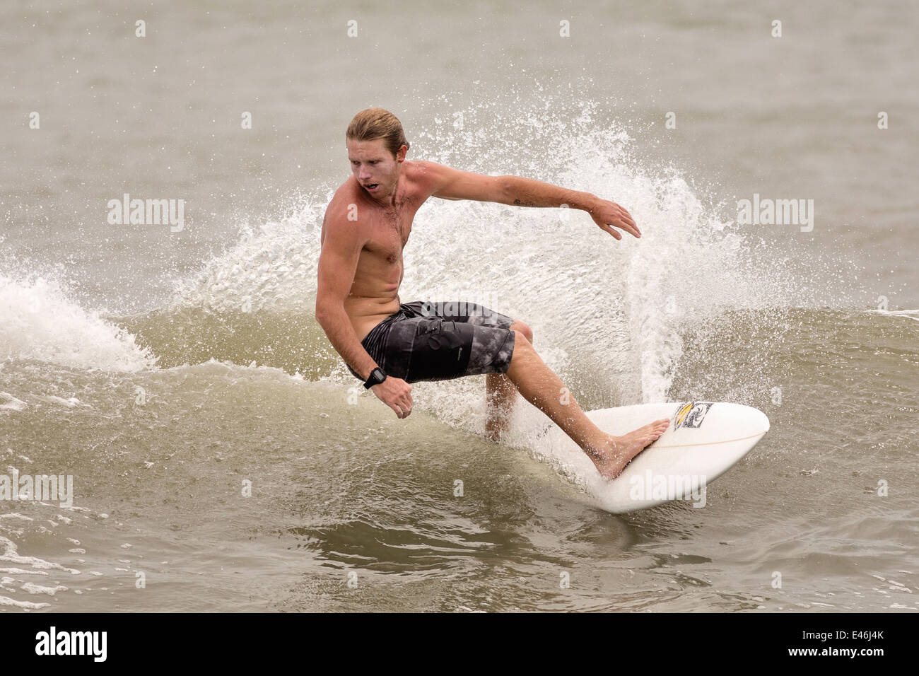 Surfers ride waves churned up as Hurricane Arthur passes off shore bringing high surf and rip tides to the beaches along the South Carolina coast July 3, 2014 in Folly Beach, SC. The first hurricane of the season passed far off the South Carolina coast causing no damage and little rain. Stock Photo