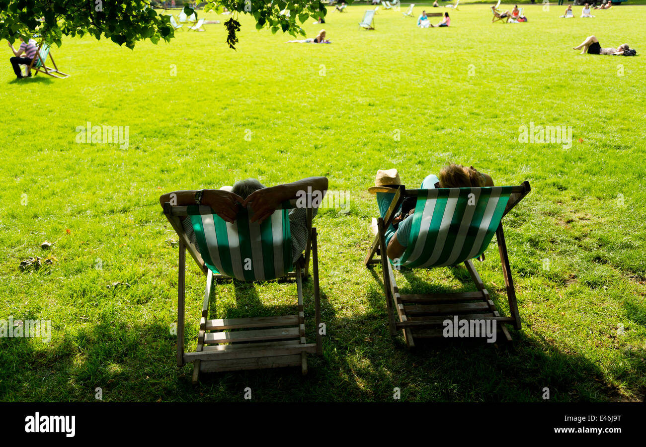 A couple lounging in deckchairs at London St. James's Park on a sunny day, England Stock Photo