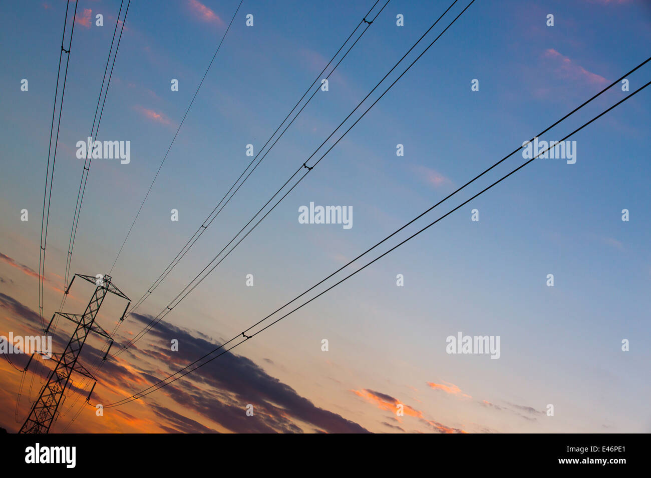 Electricity pylons at sunset silhouetted against a beautiful evening sky in English countryside. Stock Photo