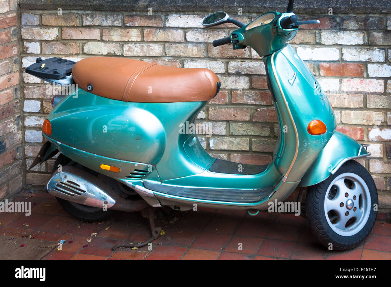Vintage scooter parked next to a brick wall Stock Photo
