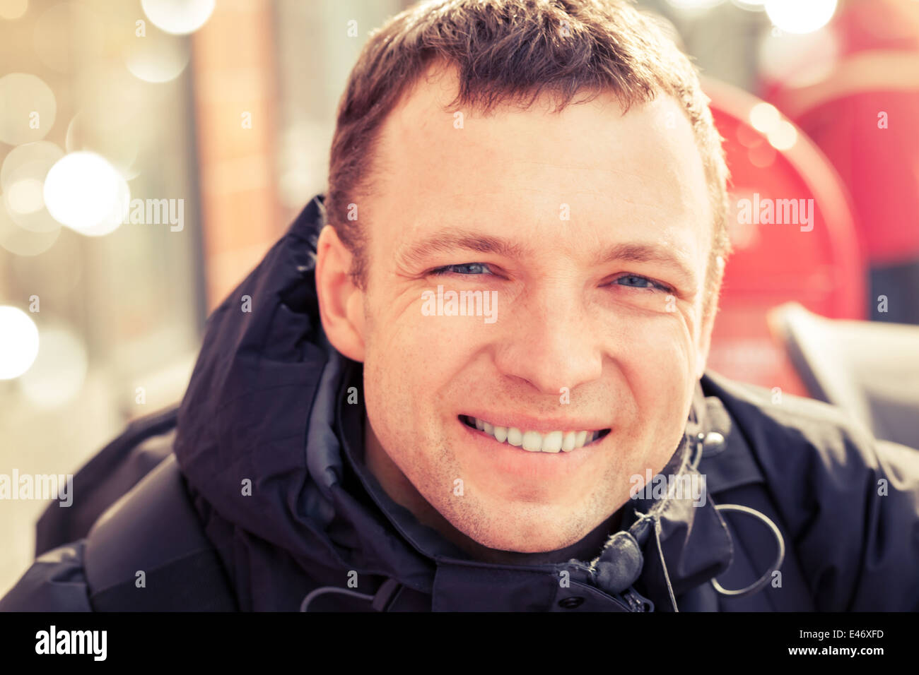 Close up city outdoor portrait of young smiling man in cold season, toned effect Stock Photo