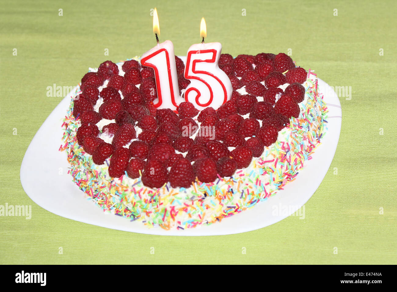 Burning birthday candles number 15 on raspberry cake Stock Photo