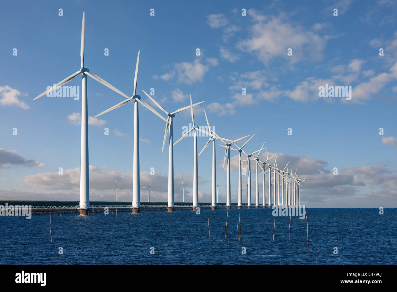 Enormous windmills standing in the sea along a Dutch breakwater Stock Photo