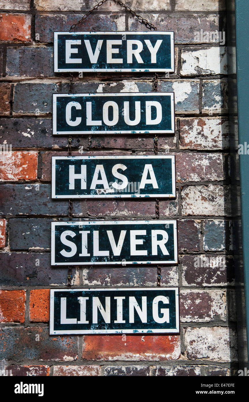 Signs on a brick wall saying 'Every cloud has a silver lining' Stock Photo