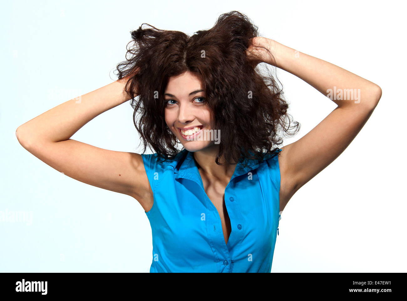 Beautiful caucasian brunette girl in blue blouse is holding her hair Stock Photo