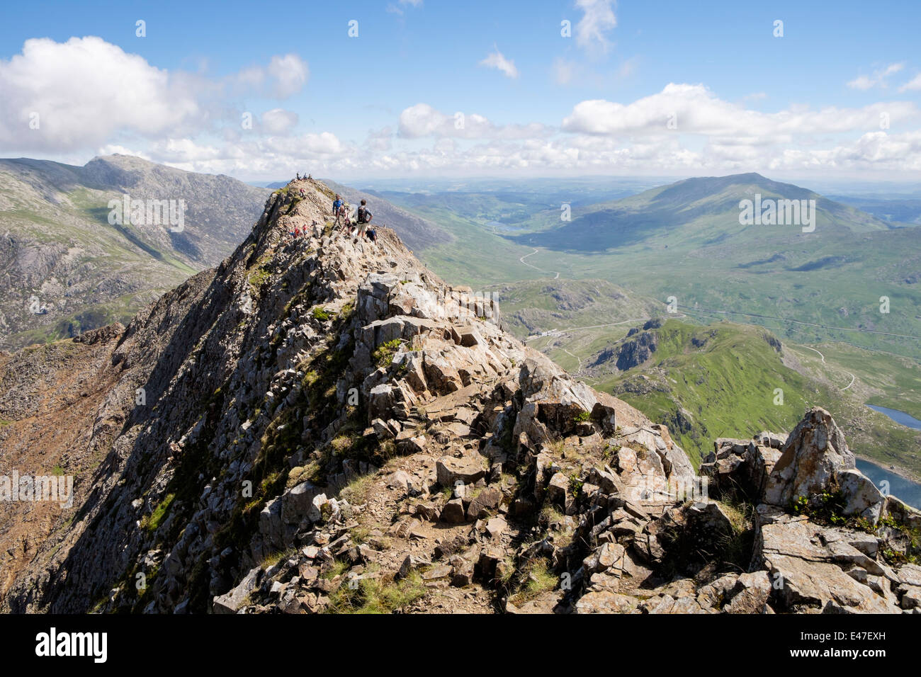 View back along red rocky Crib Goch ridge top scramble with hikers at start of Snowdon Horseshoe in mountains Snowdonia Wales UK Stock Photo