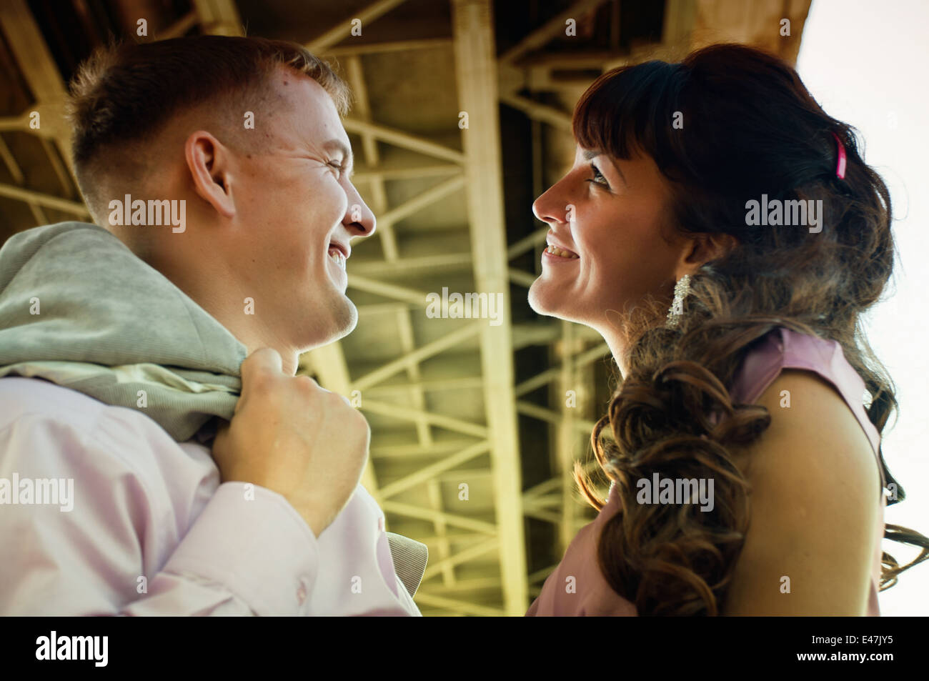 European couple under the bridge, looking at each other and smiling Stock Photo