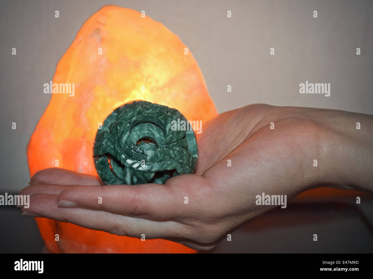 A hand of a woman with jade ball infront of salt lamp symbolizing good