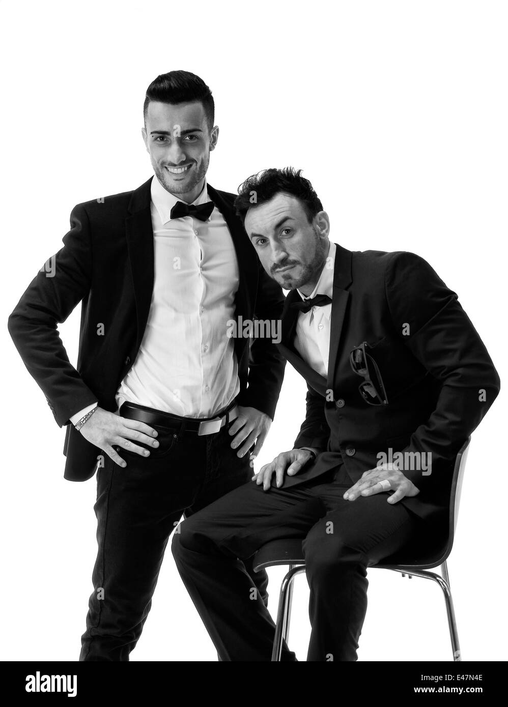 Two elegant men in suit and bowtie isolated on white, one standing, one  sitting Stock Photo - Alamy
