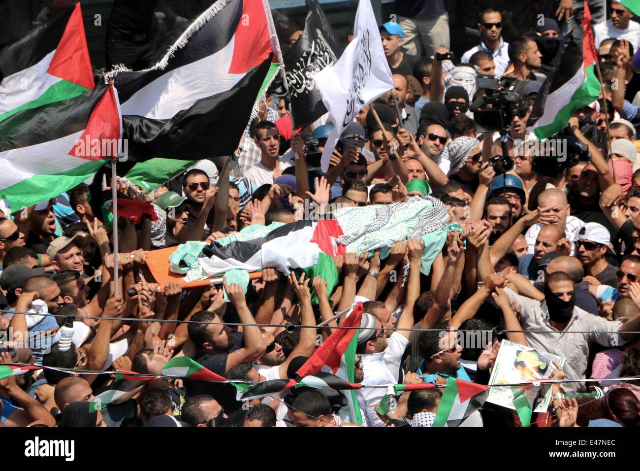 Shufat, Annexed East Jerusalem, Israel. 4th July, 2014. The body of Muhammed Abu Khdeir is carried through the town to the Mosque. People were shouting, 'Allah Akbar' and 'We have had enough!' in Arabic. Thousands of Palestinians gathered early Friday after prayers in Shufat awaiting the body of 16-year-old Muhammed Abu Khdeir. The boy was allegedly killed by Israeli settlers earlier in the week as an act of revenge against the three Israeli settlers who also were killed last week in the West Bank. Credit:  Anna Ferensowicz/Pacific Press/Alamy Live News Stock Photo