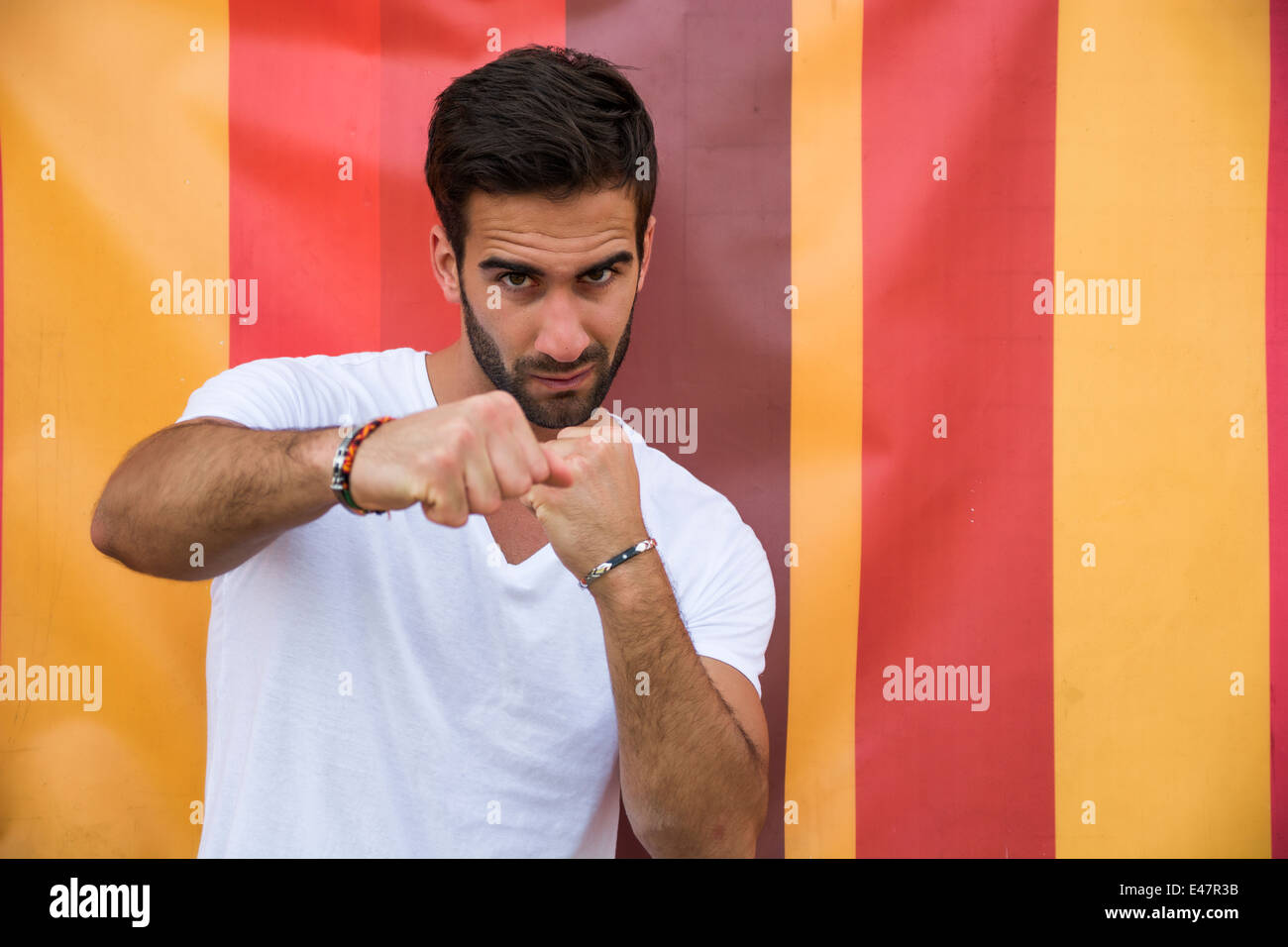 Angry handsome young man throwing punch to camera on colorful background Stock Photo