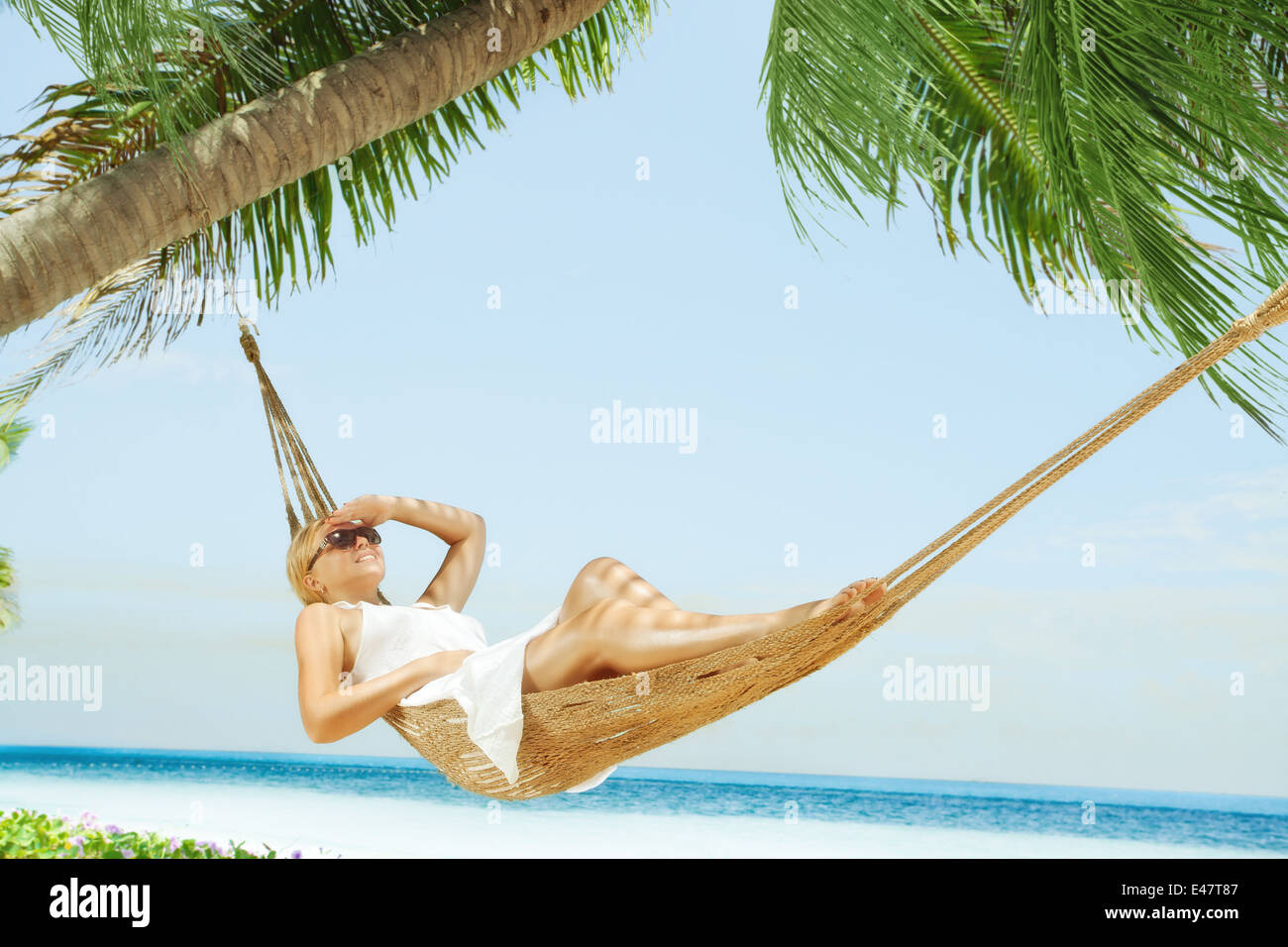 view of nice young lady swinging  in hummock on tropical beach Stock Photo