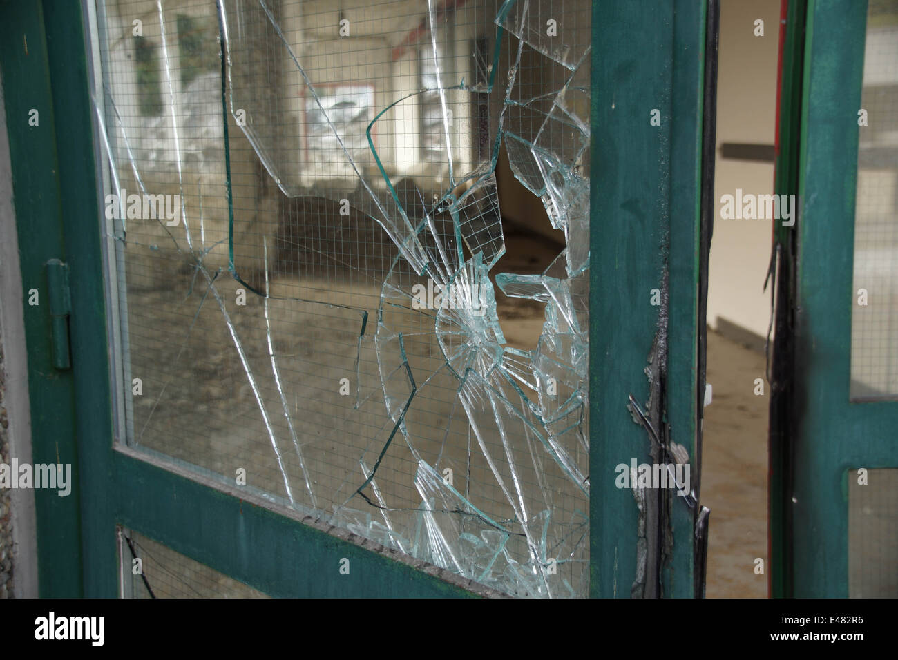 Broken glass door with green metal frame Stock Photo