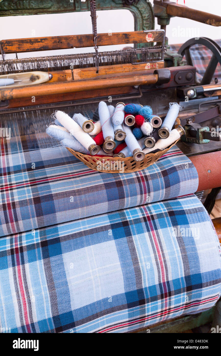 Highland Tartan fabric and bobbins on traditional weaving loom at Lochcarron Weavers in Lochcarron in the Highlands of SCOTLAND Stock Photo
