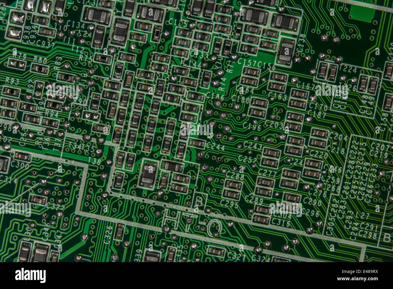 Macro-photo of surface mount (SMT) circuit board / motherboard showing tiny resistors, capacitors and linking wiring. Wiring inside computer. Stock Photo